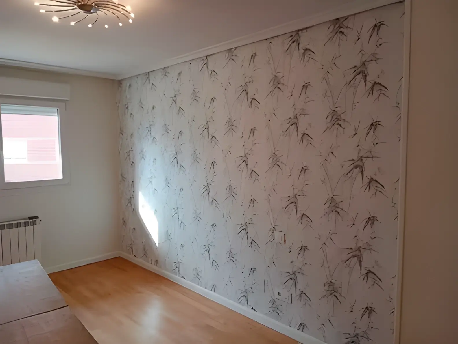Los Pintores Leganés colocando papel pintado en pared de acento de habitación luminosa